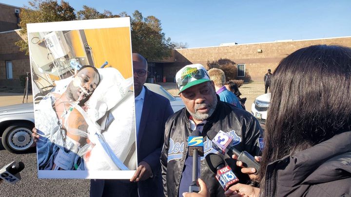 Rodney Wells (center) stands beside a poster showing stepson Tyre Nichols, who died in the custody of police in Memphis, Tennessee.