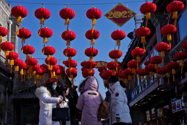 Women walk under red lanterns hanging on a shopping alley near the Houhai Lake for celebrating the Lunar New Year in Beijing, on Jan. 16, 2023. 