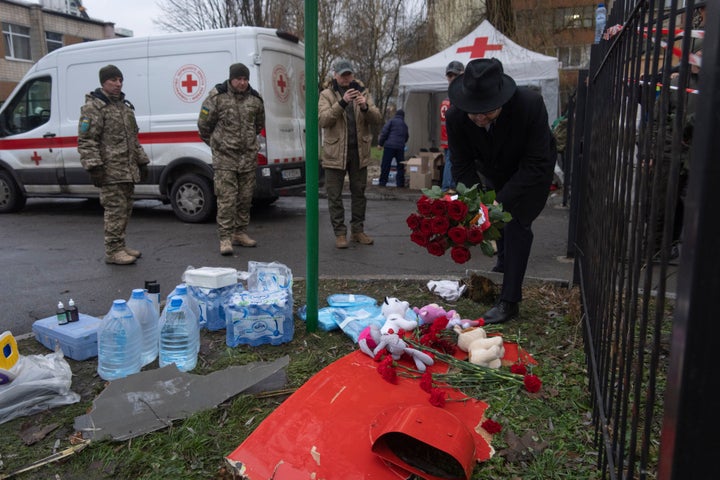 A man lays flowers and children toys near a fragment of a helicopter crashed at a kindergarten in Brovary, in the outskirts of Kyiv, Ukraine, on Jan. 18, 2023.