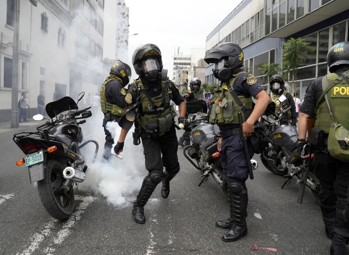 A police officer throws away a tear gas canister that was thrown back at them by anti-government protesters who traveled to the capital from across the country to march against Peruvian President Dina Boluarte in Lima, Peru, on Jan. 18, 2023.