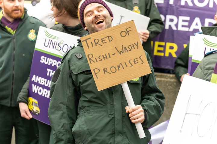 Striking ambulance worker holds a placard expressing his opinion in Westminster.