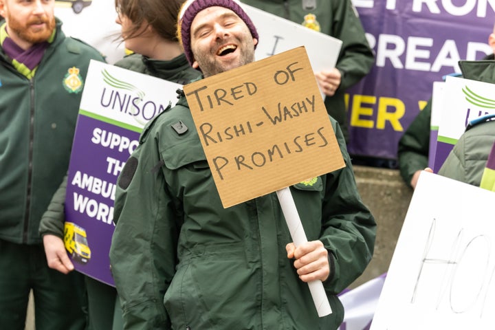 Striking ambulance worker holds a placard expressing his opinion in Westminster.