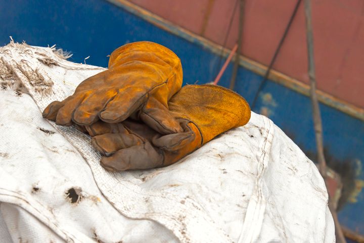 two brown leather work gloves lie on white tarpaulin