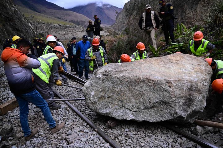 TOPSHOT - Workers attempt to remove a rock placed by rioters on the railway track to block the train's passage to and from the Inca citadel of Machu Picchu in Ollantaytambo, Peru, on December 17, 2022. - Around 5,000 tourists have been left stranded in Cusco, the gateway city to Peru's top attraction Machu Picchu, by deadly protests against the ousting of president Pedro Castillo, a local mayor said on Friday. Rail service to Machu Picchu has been suspended since Tuesday. (Photo by MARTIN BERNETTI / AFP) (Photo by MARTIN BERNETTI/AFP via Getty Images)