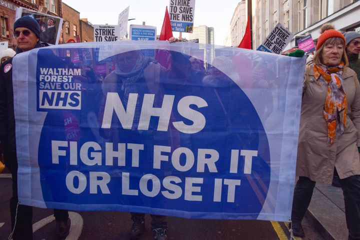 Protesters march along Tottenham Court Road with a banner in support of the NHS during the demonstration.