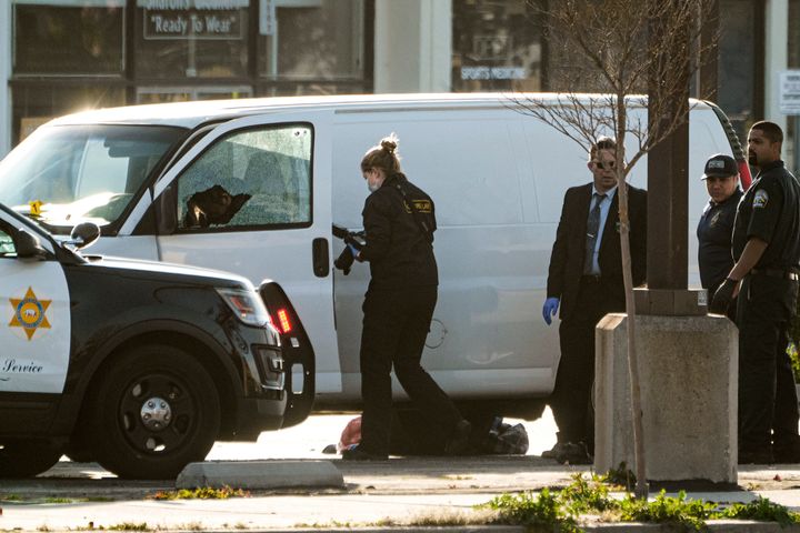 A forensic photographer takes pictures of a body in the front seat of a van before the coroner retrieves it in Torrance, Calif., on Jan. 22, 2023. 