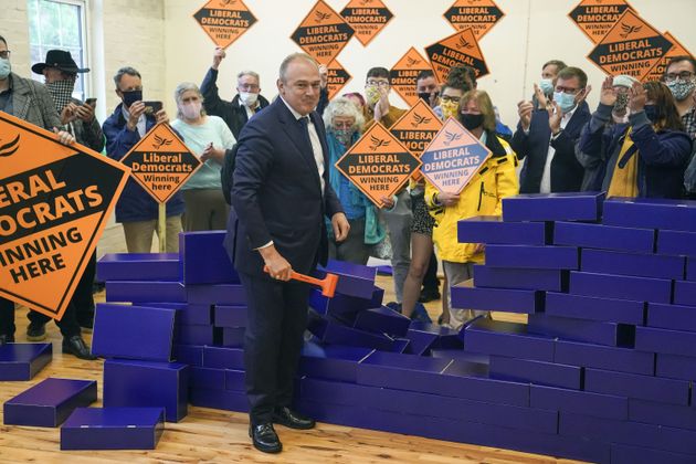 Lib Dem leader Ed Davey knocks down a blue wall following a by-election victory. 