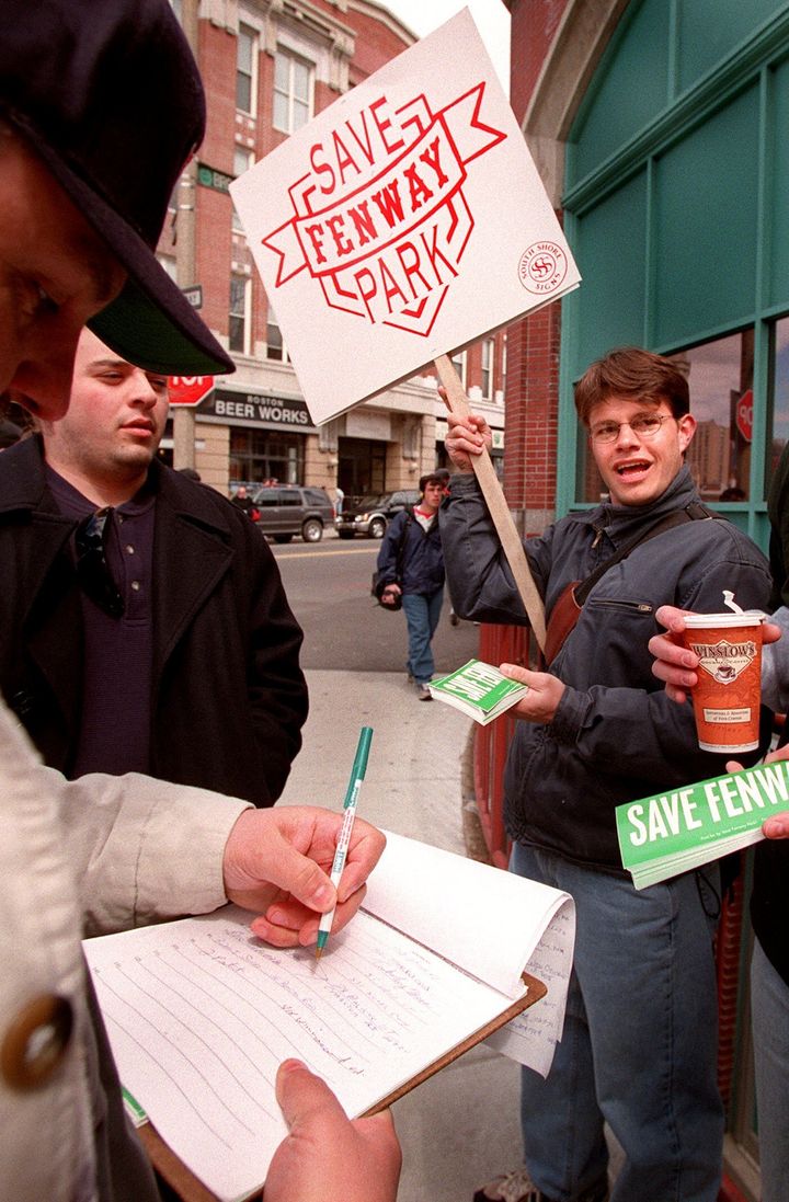 1999年のシーズン開幕日に「Save Fenway Park（フェンウェイ・パークを守れ）」のプラカードを掲げ、反対運動に署名する人々（1999年4月13日）