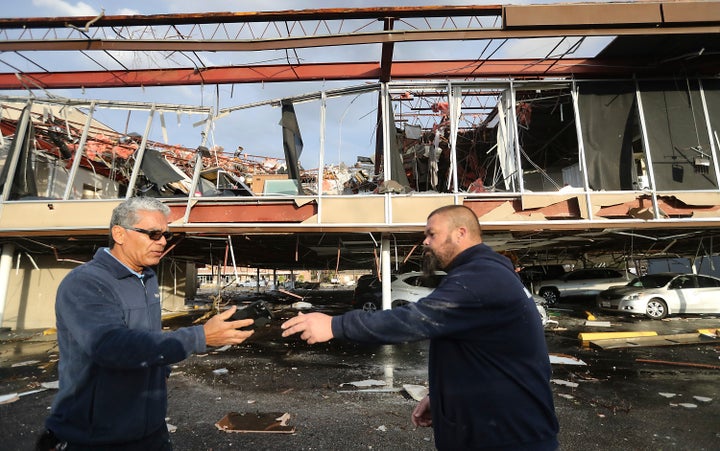 Mr. Electric employees Héctor Vázquéz, left, and Lucas Perry pass off a phone outside their office building where they were working when a powerful storm system hit, spawning a tornado, on Jan. 24, 2023, in Deer Park, Texas. 