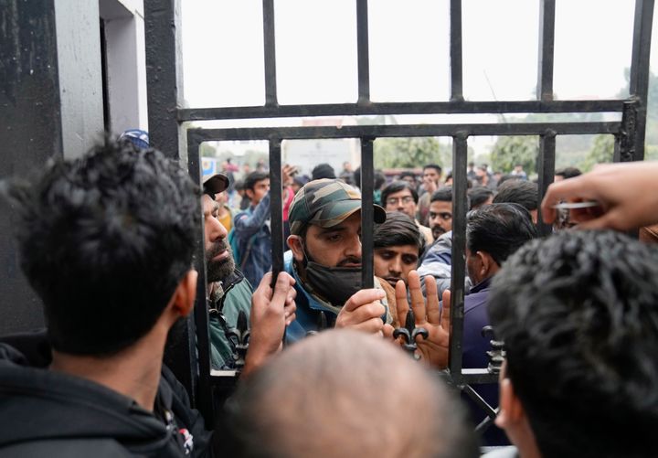 Security personnel speak to people at the main gate of Jamia Millia Islamia University in New Delhi on Wednesday.  Tensions at the university escalated after a student group said they were planning to screen a banned documentary examining Modi's role during the 2002 anti-Muslim riots, prompting dozens of police officers armed with tear gas and riot gear to gather at the campus gates.