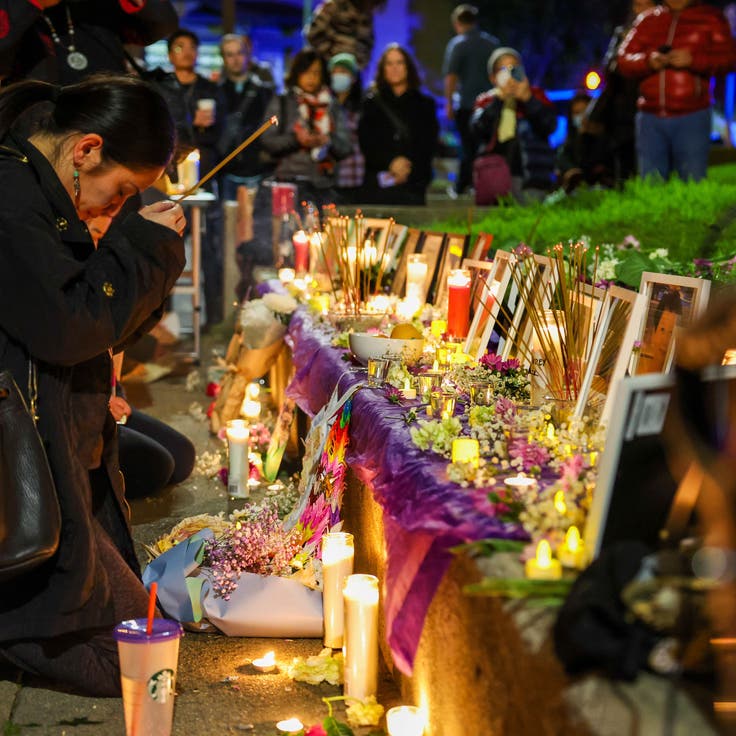 Carina Lieu pays respects at a makeshift memorial in honor of the mass shooting victims of Monterey Park, Half Moon Bay and East Oakland during a candlelight vigil at Wilma Chan Park in Oakland on Jan. 25.