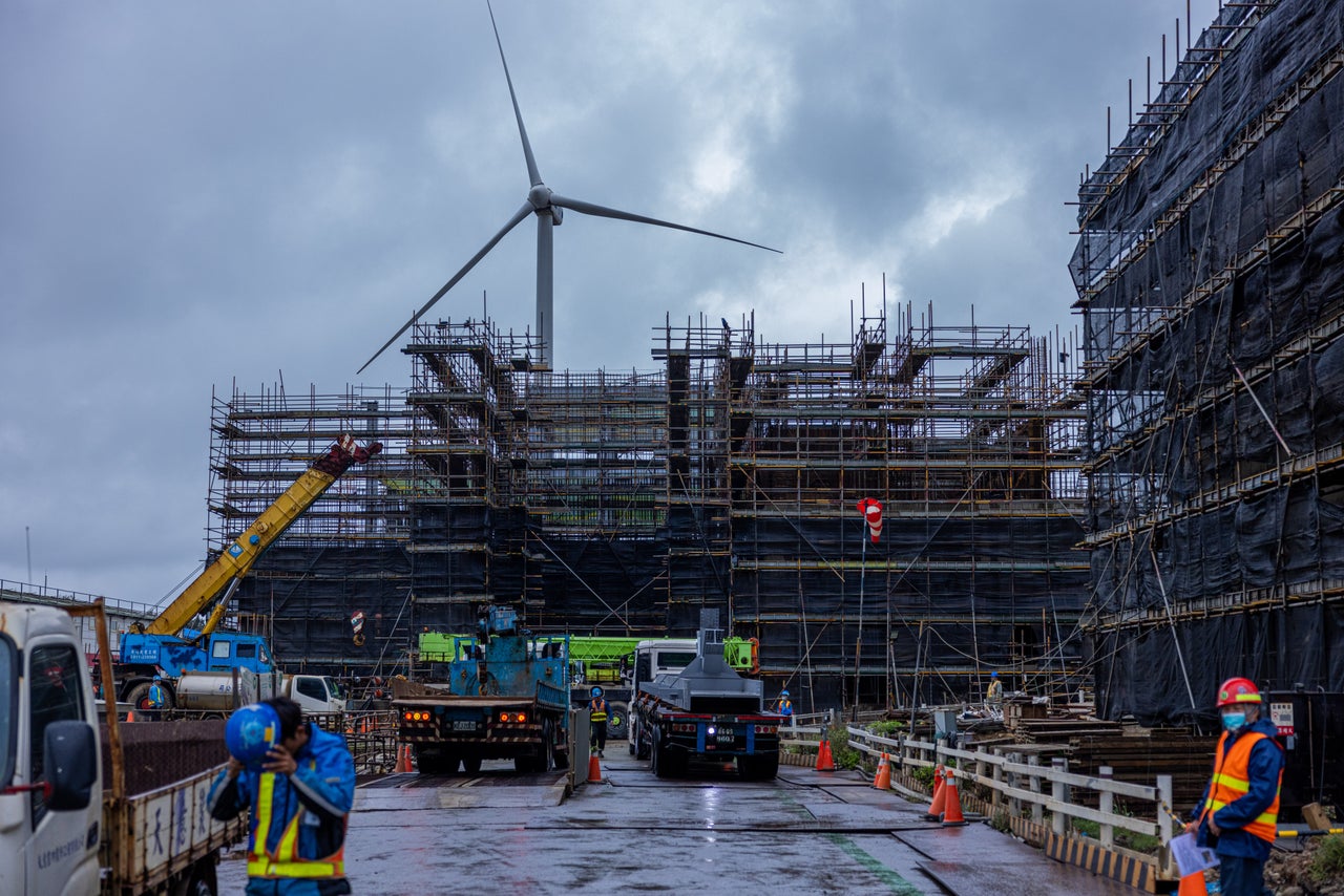 A wind turbine rises behind a construction site for a natural gas power plant in Taoyuan, Taiwan.