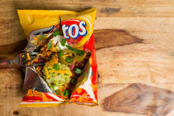 Frito Pie features a big old ladle of chili poured on top of a bag of Fritos, topped with sour cream, salsa and guacamole.