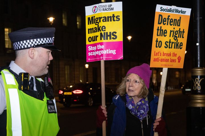 A Metropolitan Police officer speaks to a campaigner during a protest rally by trade union members opposite Downing Street on 30 January 2023