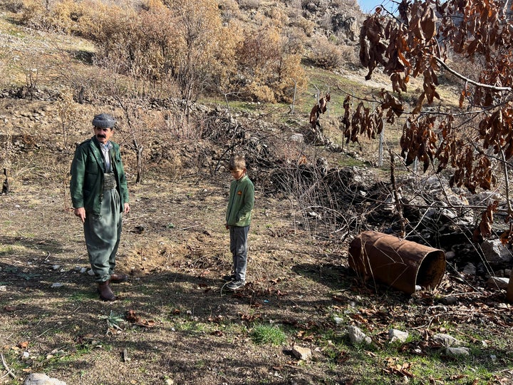 Ο Oμάρ Αμπντουλάχ στέκεται με τον εγγονό του στην αυλή δίπλα στο σπίτι του στο χωριό Σαράρο, όπου ισχυρίζεται ότι αρκετοί πύραυλοι έπεσαν κατά τη διάρκεια του τουρκικού βομβαρδισμού πέρυσι, Ιράκ, στις 27 Δεκεμβρίου 2022.