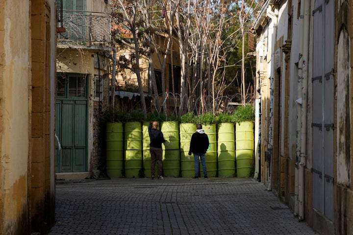 Δύο άνδρες στέκονται μπροστά από οδοφράγματα που χωρίζουν τους Ελληνοκύπριους με την κατεχόμενη Λευκωσία. Κύπρος, Σάββατο, 28 Ιανουαρίου 2023. (AP Photo/Petros Karadjias)