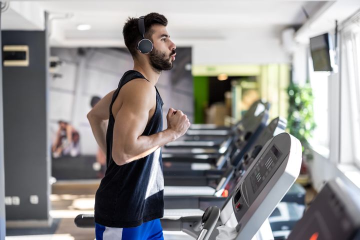 A young athlete is exercising on a treadmill and listening to music.