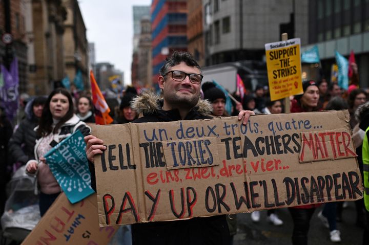 A teacher holds a placard while taking part in a protest organised NEU and other affiliated trade unions in Saint Peter's square, in Manchester, on February 1, 2023 as part of a national strike day