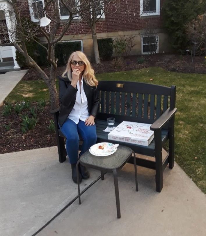 The author sharing a pizza outdoors with her son, who is sitting on the opposite side of the courtyard, in Pittsburgh in September. "Note my N95 mask hanging in the tree," she writes.
