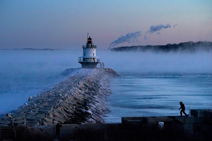 A man walks on sea wall near Spring Point Ledge Light, Saturday, Feb. 4, 2023, in South Portland, Maine.