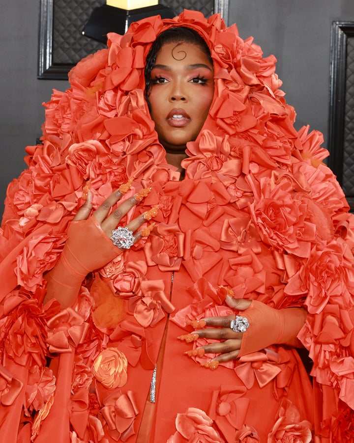 Lizzo rocks an orange, flowery look on the red carpet ahead of Sunday's Grammy Awards.