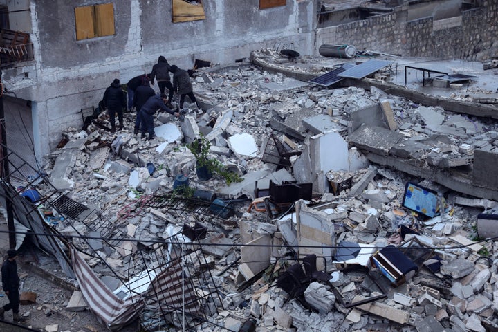 Residents search for victims and survivors amidst the rubble of a building that collapsed, following an earthquake in the village of Azmarin, near the Turkish border in the north of Syria's rebel-held northwestern Idlib province, early on Feb. 6, 2023. 