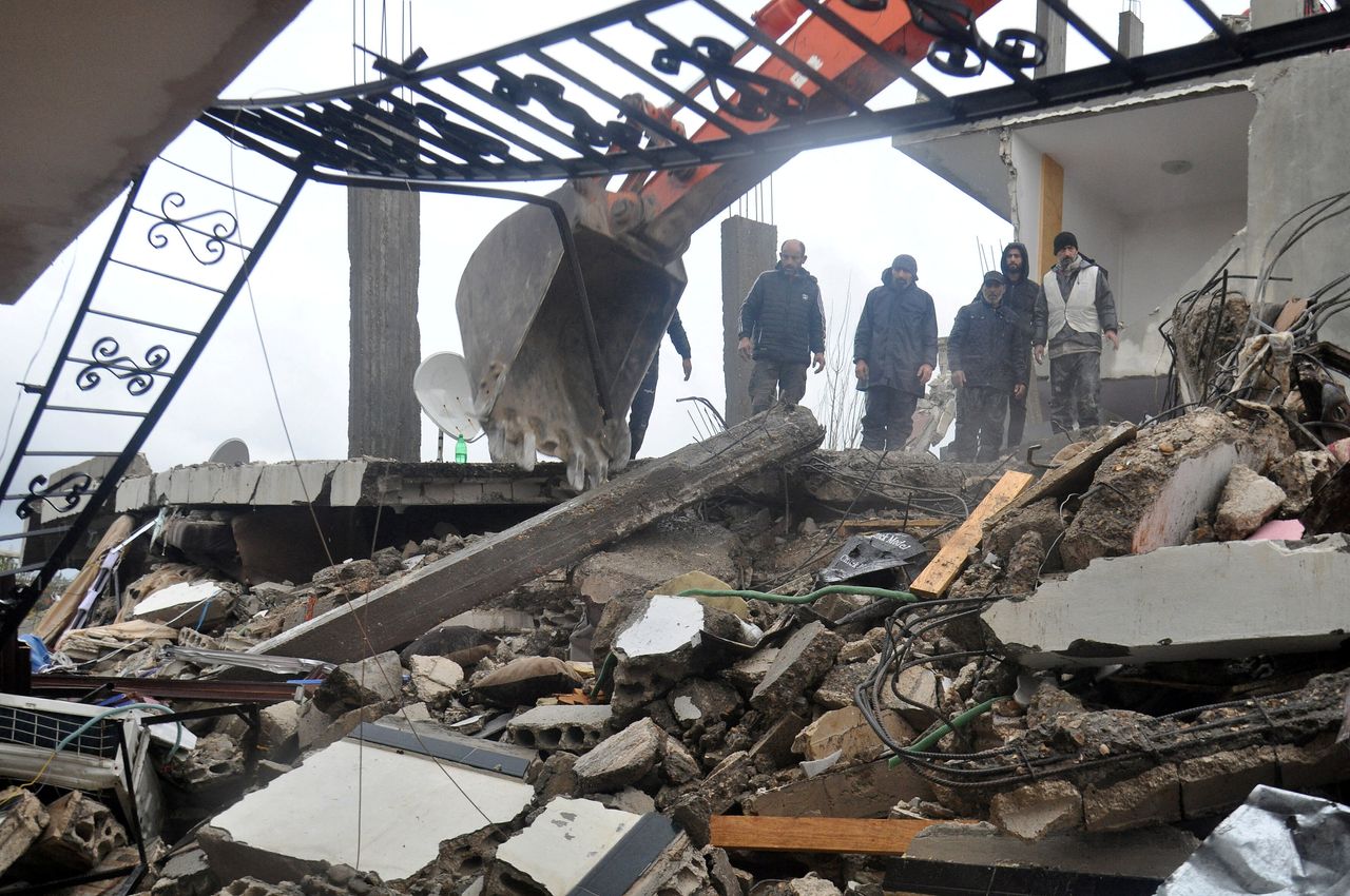 Οι διασώστες στέκονται στα ερείπια ενός κτιρίου που κατέρρευσε, μετά από σεισμό, στη Λαττάκεια της Συρίας, 6 Φεβρουαρίου 2023