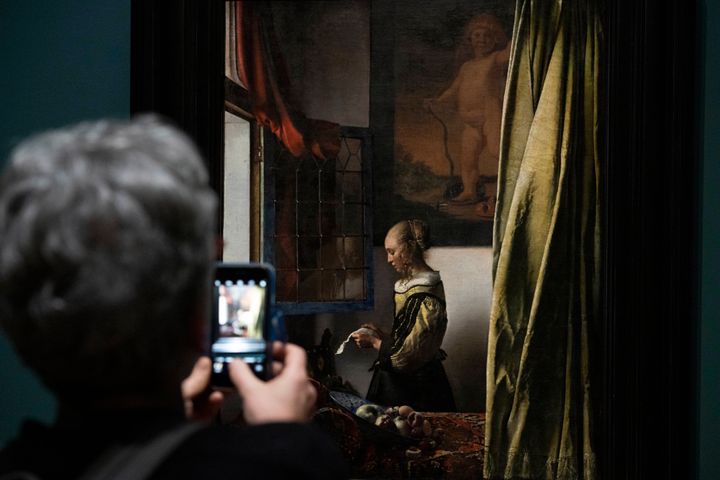 Γυναίκα φωτογραφίζει το έργο «Κορίτσι που διαβάζει γράμμα μπροστά σε ανοιχτό παράθυρο», Rijksmuseum, Άμστερνταμ, Δευτέρα, 6 Φεβρουαρίου 2023. (AP Photo/Peter Dejong)