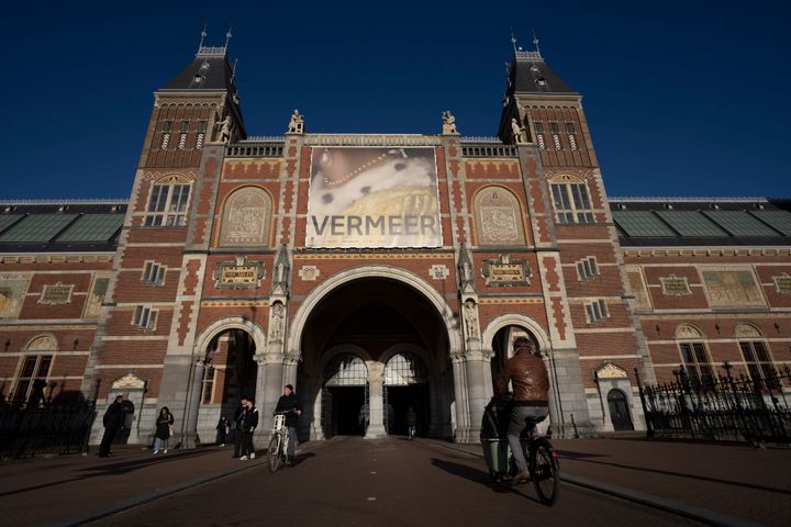 Ποδηλάτες περνούν κάτω από τη γιγαντοαφίσα της μεγάλης έκθεσης στο Rijksmuseum (AP Photo/Peter Dejong)