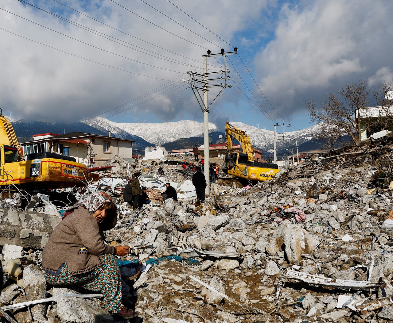 A woman reacts as she sits amidst rubble and damages following an earthquake in Gaziantep, Turkey, February 7, 2023. REUTERS/Suhaib Salem