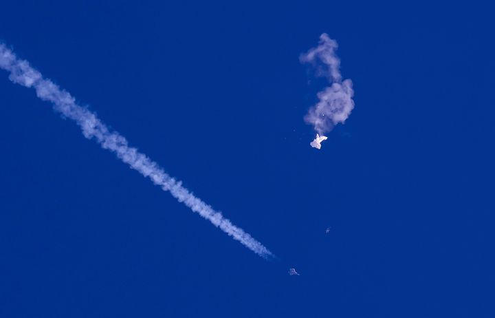 In this photo provided by Chad Fish, the remnants of a large balloon drift above the Atlantic Ocean, just off the coast of South Carolina, with a fighter jet and its contrail seen below it, Feb. 4, 2023. (Chad Fish via AP, File)