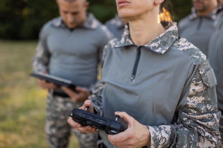 Caucasian woman from the military team, driving the drone while using drone remote control