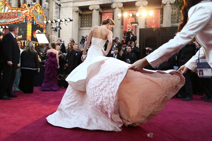 Actress Jennifer Lawrence gets a little help with her gown at the 2013 Oscars.