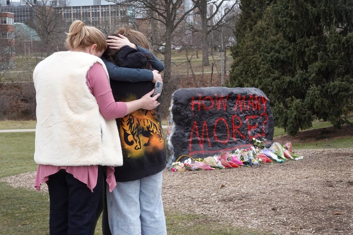 People leave flowers, mourn and pray at a makeshift memorial at "The Rock" on the campus of Michigan State University on Feb. 14, 2023. A gunman opened fire at two locations on the campus the day prior, killing three students and injuring several others.