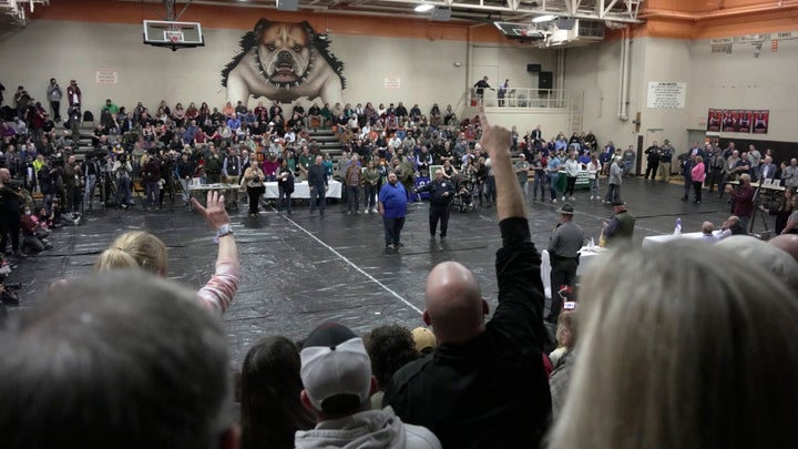 A man raises his hand with a question for East Palestine, Ohio Mayor Trent Conaway, center, during a town hall meeting at East Palestine High School in East Palestine, Ohio, on Feb. 15, 2023.