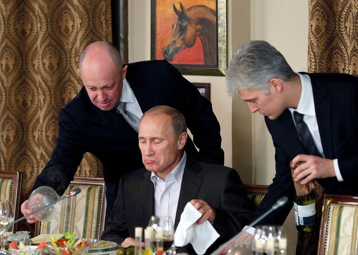 Evgeny Prigozhin assists Russian Prime Minister Vladimir Putin during a dinner with foreign scholars and journalists in 2011