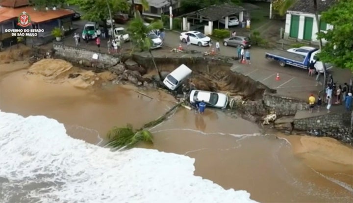 This photo provided by the Sao Paulo Government shows vehicles fallen from an elevated area along the beach in Sao Sebastiao, east of Sao Paulo, Brazil, Sunday, Feb. 19, 2023, after it was damaged by a severe weather system went through the area.