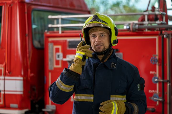 Firefighter standing near fire truck with fire hose,Fireman wearing full protective equipment.