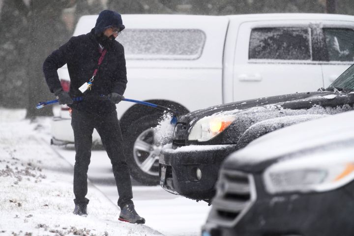 A man cleans the snow off of his vehicle as a winter storm arrives Feb. 16, 2023, in Wheeling, Ill. 
