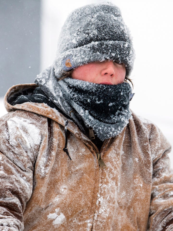 Barret Goff, covered in an icy drizzle, braves the heavy early morning snow to clear the Alan's Auto Sales lot with a snow blower on Feb. 16, 2023, in Lincoln, Neb. 