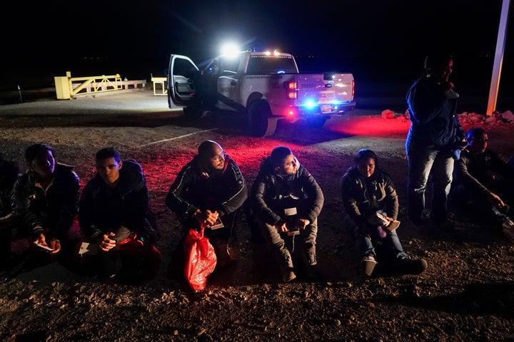 Migrants wait to be processed after crossing the border on Jan. 6, 2023, near Yuma, Ariz. The Biden administration says it will generally deny asylum to migrants who show up at the U.S. southern border without first seeking protection in a country they passed through.