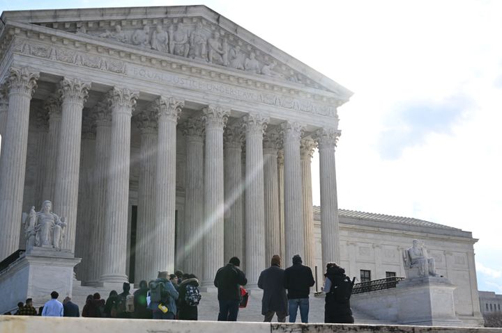 People wait in line outside the U.S. Supreme Court on Tuesday to hear oral arguments in two cases that test Section 230, the law that provides tech companies a legal shield over what their users post online.