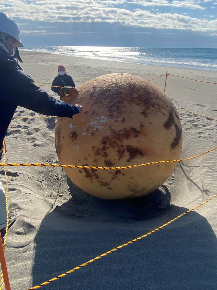 Authorities rope off and examine the sphere Wednesday on a beach in Hamamatsu, Japan.