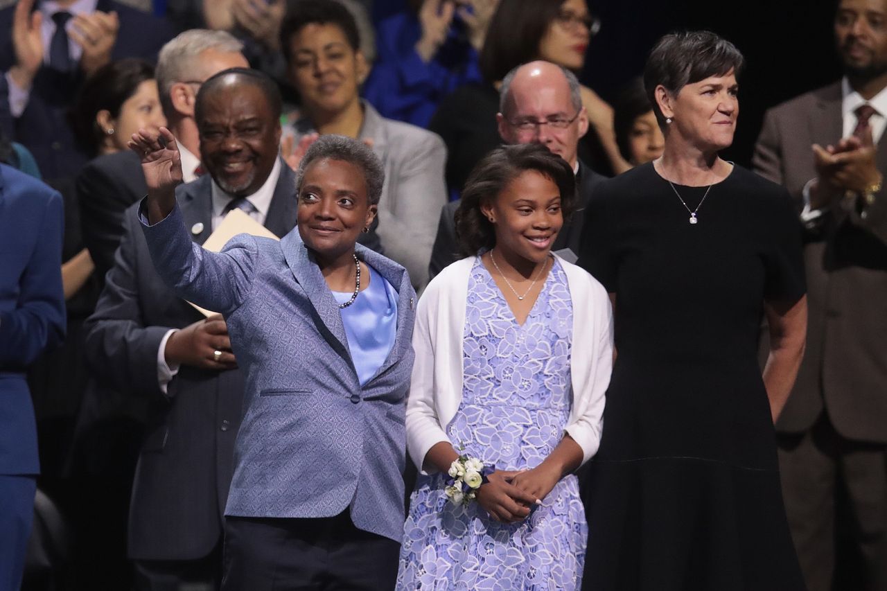 Chicago Mayor Lori Lightfoot waves to the crowd at her inauguration in May 2019. Her wife, Amy Eshleman, and daughter Vivian stand by her side.
