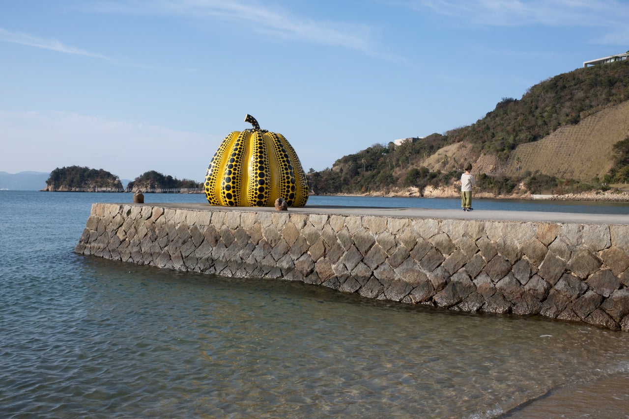 A boy stands in front of Yayoi Kusama’s “Pumpkin” at Benesse House Museum. The sculpture was restored and placed here in October 2022 after the original was damaged by a typhoon.