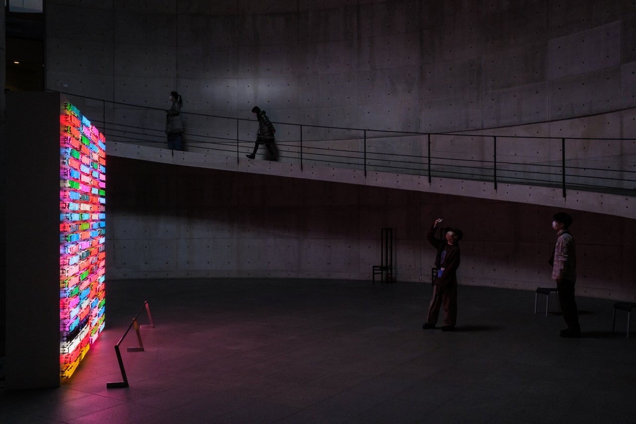 Museum visitors walk by Bruce Nauman's "100 Live and Die" at Benesse House Museum in Naoshima.