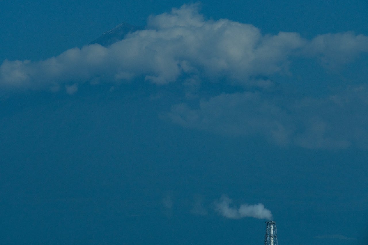 Mount Fuji and a factory chimney seen from the Tokaido Shinkansen (bullet train).