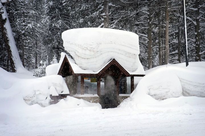 A person sits at a snow-covered bus stop in Olympic Valley, California on Friday.