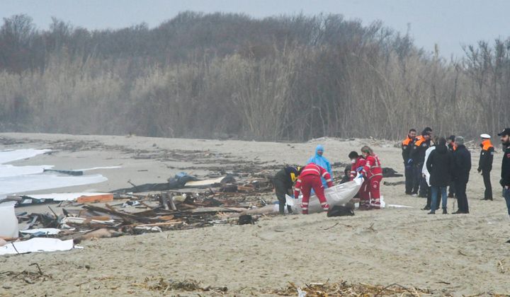 Rescuers are seen handling a body bag at the site of the shipwreck in Steccato di Cutro, south of Crotone.