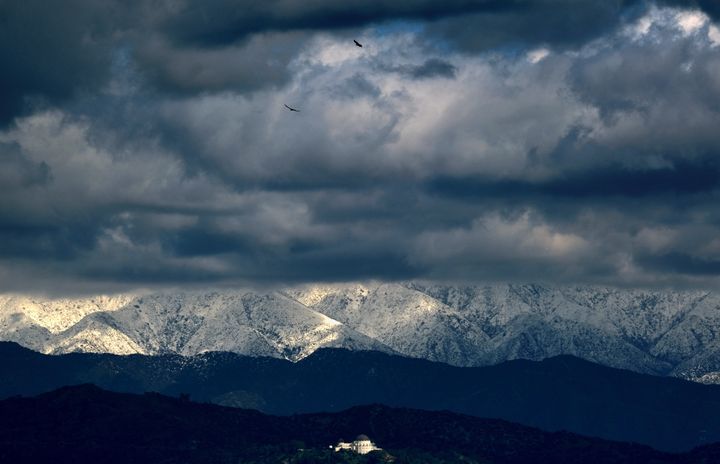 Storm clouds and snow are seen over the San Gabriel mountain range behind Griffith Observatory in the Hollywood Hills, in Los Angeles on Feb. 26, 2023. 